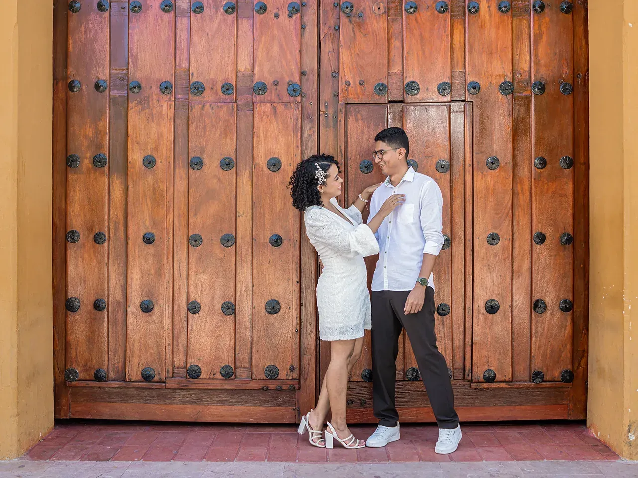 Brian y Lina frente a un portón de madera antiguo